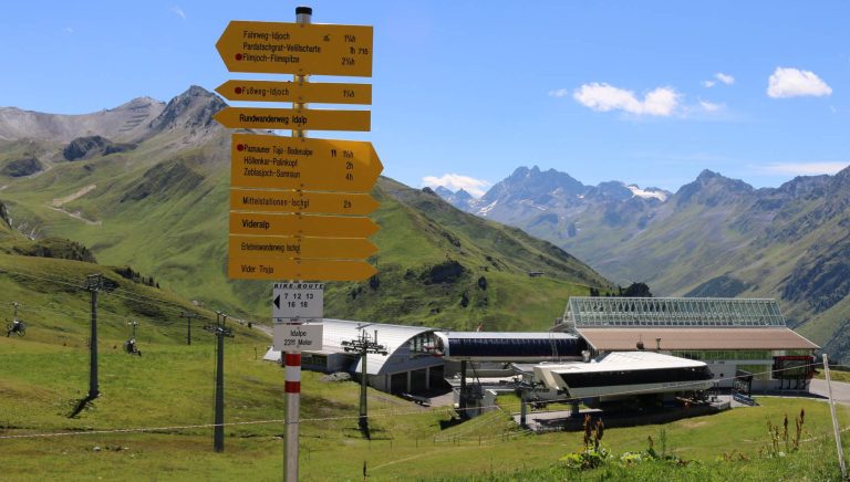 Wegweiser und Bergbahnstation in Ischgl und Galtür