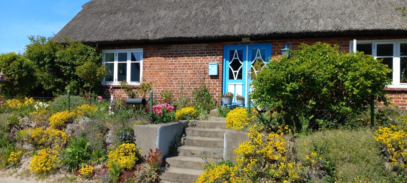 Groß Zicker - historisches Reetdachhaus Fassade historisches Reetdachhaus mit buntem Steingarten in Groß Zicker auf Rügen