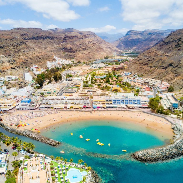 Blick auf Puerto Mogan mit Stränden und umliegenden Bergen.