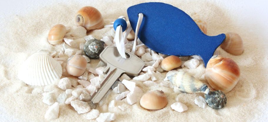 Schlüssel für Ferienwohnung mit Muscheln im Sand