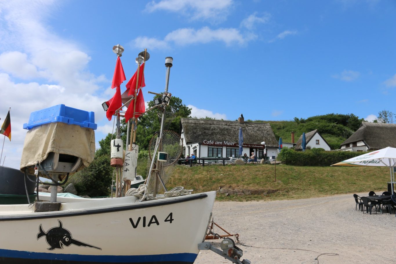 Rügen - Fischerboot im Fischerdorf Vitt Fischerboot mit roten Fahnen am Cafe am Meer in Vitt